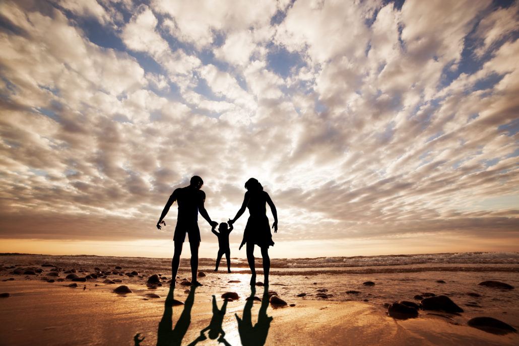 Happy family together hand in hand on the beach at sunset. Summer time, parents, child